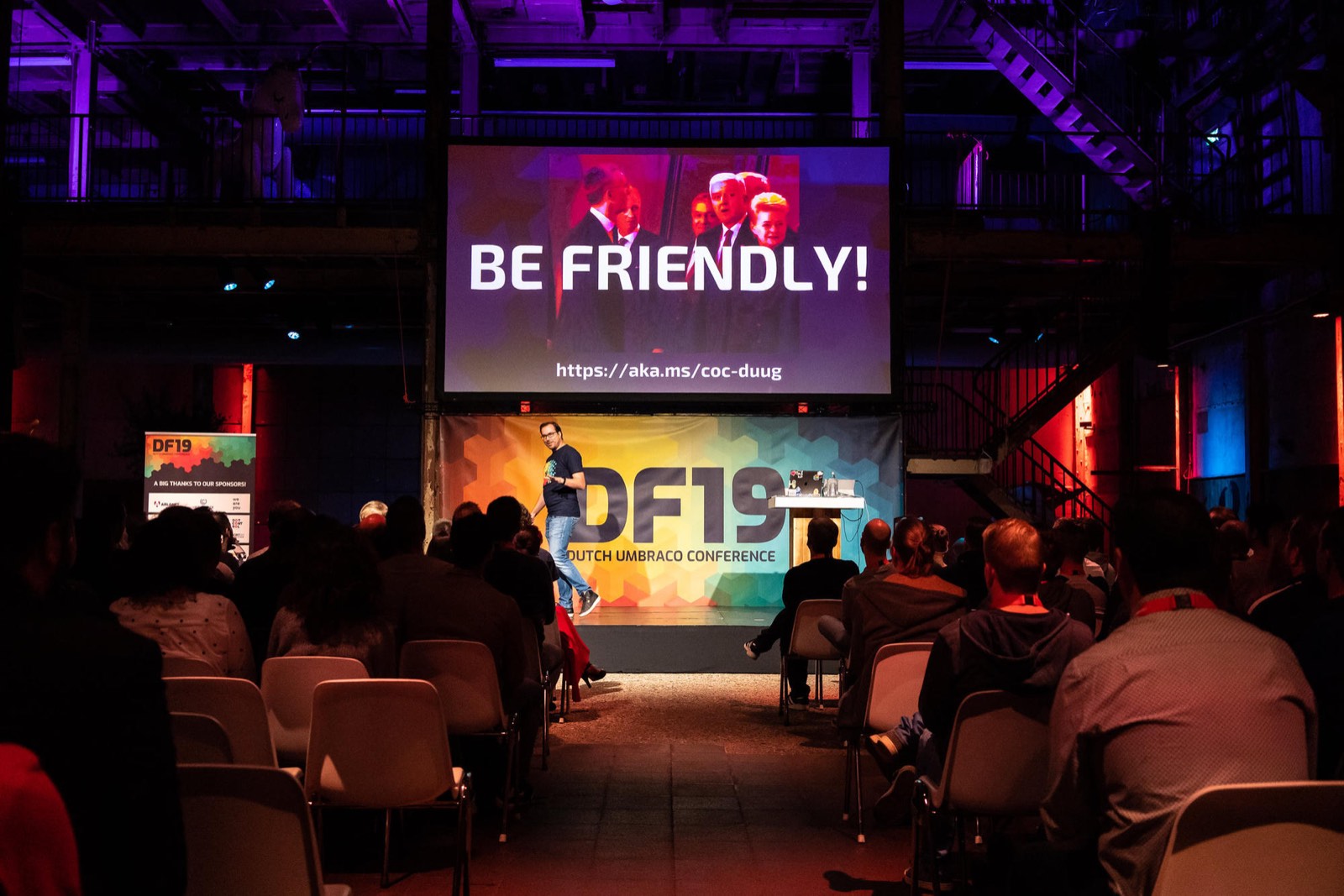 Speaking at DF19, the Dutch Umbraco Conference, with a "Be friendly!" code of conduct slide on the big screen above the stage